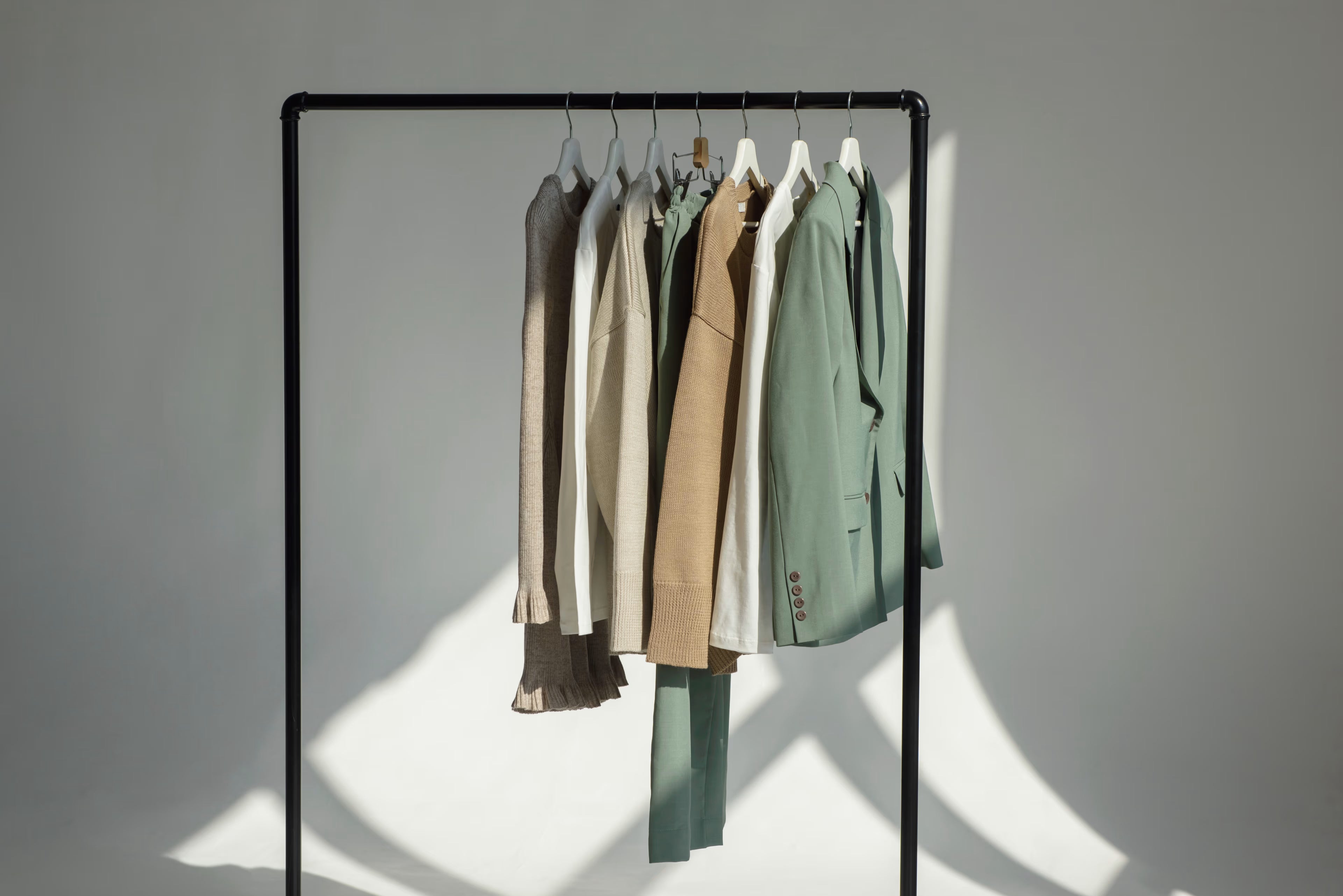 Clothing rack with five jackets in various colors against a plain background